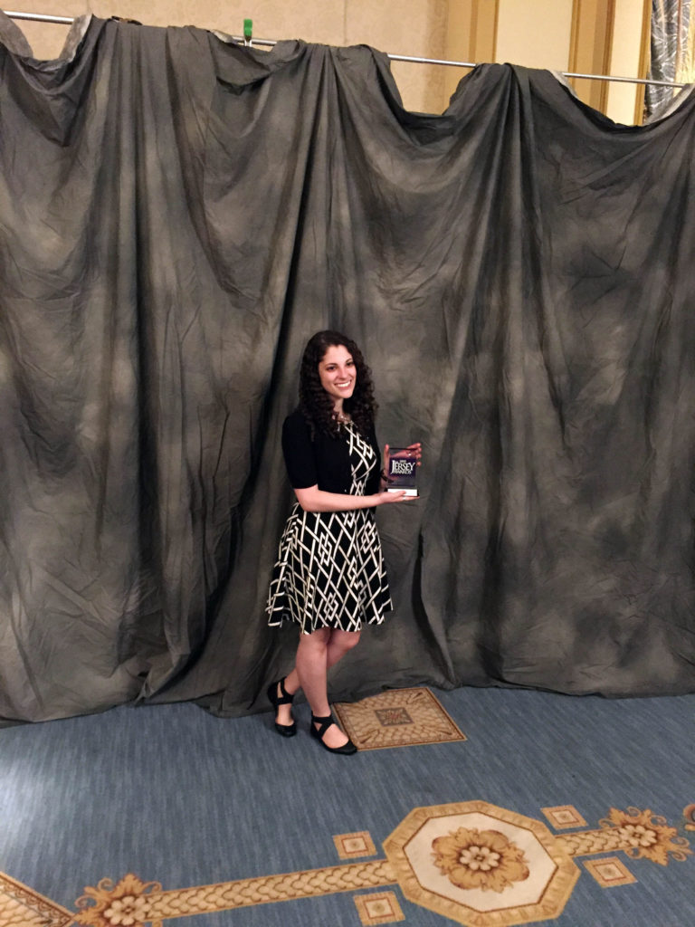 Jenn Rothshchild poses with a new award from NJ Ad Club for some of our design work